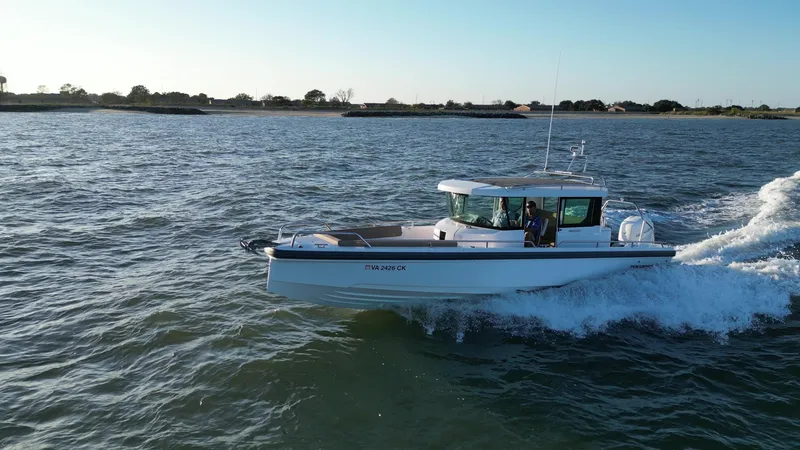 Slide: The Image of 2019 Axopar 28 CABIN boat cruising on open water under clear skies. - 4