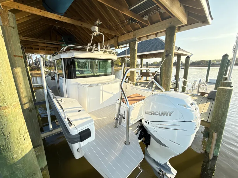 Slide: The Image of 2019 Axopar 28 CABIN boat docked under wooden shelter with Mercury outboard engine. - 40