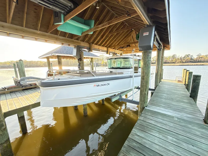 Slide: The Image of 2019 Axopar 28 CABIN boat docked under a wooden shelter by the water. - 41