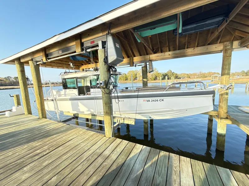 Slide: The Image of 2019 Axopar 28 CABIN boat docked under a wooden shelter by the water. - 43