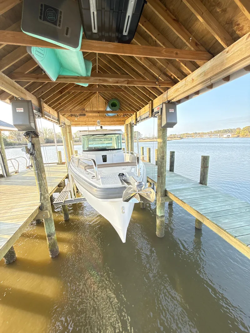 Slide: The Image of 2019 Axopar 28 CABIN boat docked under a wooden shelter by the water. - 47