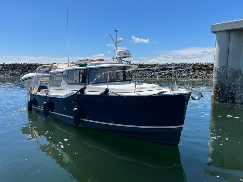 Slide: The Image of 2020 Ranger Tugs R-27 boat docked in calm waters under a clear blue sky. - 1