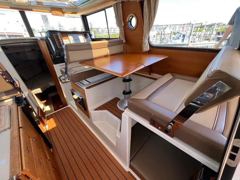 Slide: The Image of 2020 Ranger Tugs R-27 interior with wood accents, seating, and table in a well-lit cabin. - 19