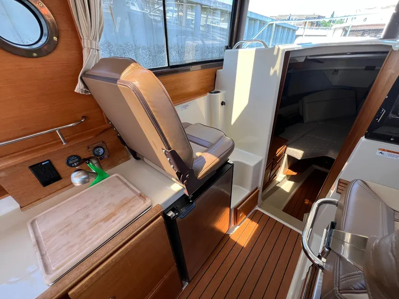 Slide: The Image of 2020 Ranger Tugs R-27 interior with helm seat, wood accents, and cabin entrance. - 21