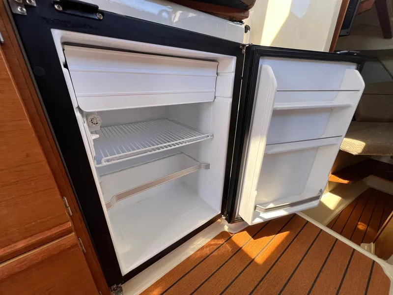 Slide: The Image of Open refrigerator inside 2020 Ranger Tugs R-27 boat, featuring wooden flooring and compact design. - 22