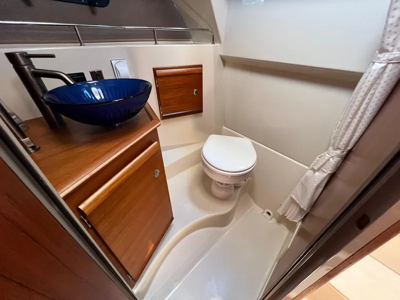 Slide: The Image of 2020 Ranger Tugs R-27 bathroom with blue vessel sink and wooden cabinetry. - 25
