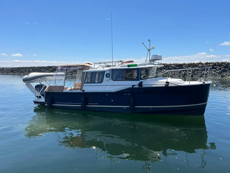 Slide: The Image of 2020 Ranger Tugs R-27 boat on calm water under clear blue sky. - 4