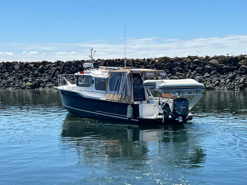 Slide: The Image of 2020 Ranger Tugs R-27 boat on calm water, rocky shoreline background. - 8