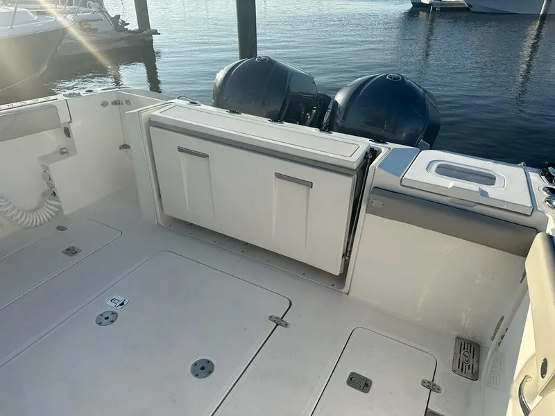 Slide: The Image of 2022 Pursuit S 328 Sport boat deck with storage compartments and dual outboard engines. - 12