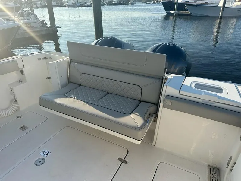 Slide: The Image of 2022 Pursuit S 328 Sport boat with cushioned seating and dual engines at a marina. - 13