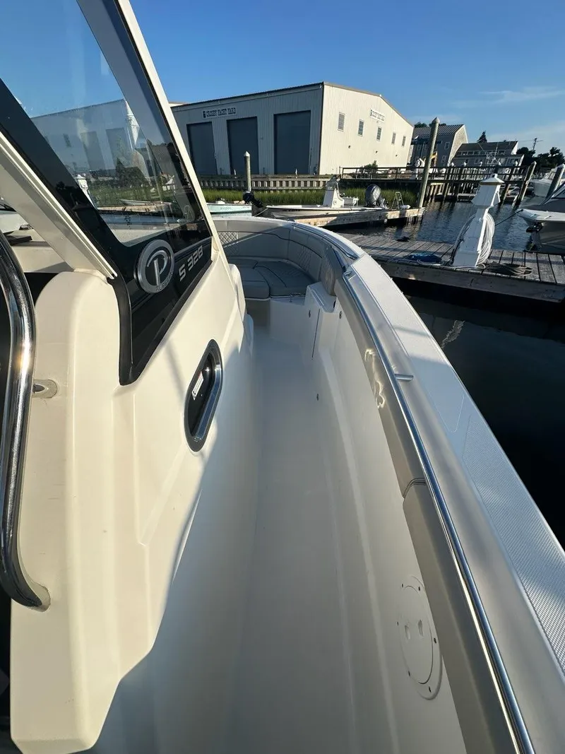 Slide: The Image of 2022 Pursuit S 328 Sport boat docked at marina under clear blue sky. - 14