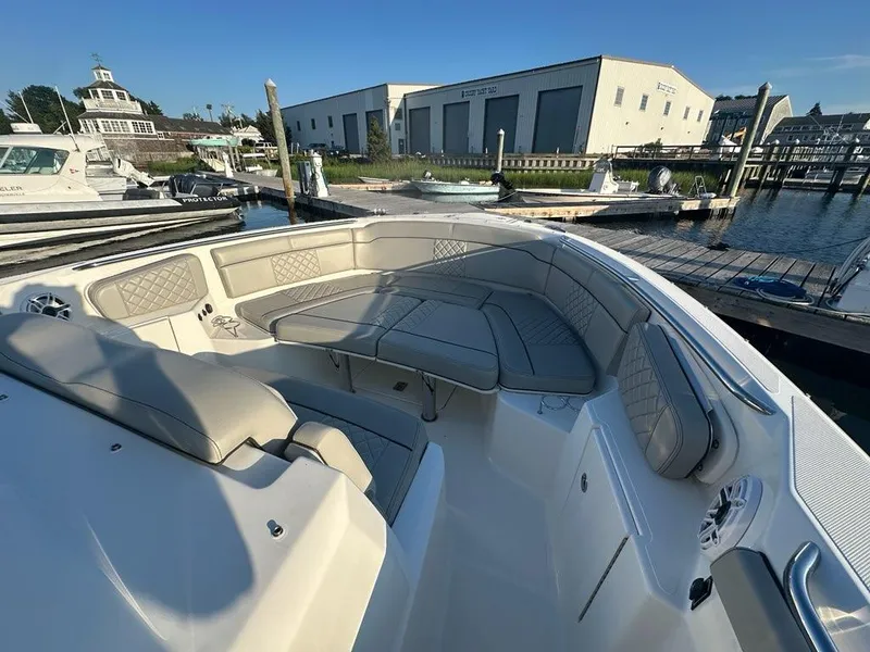 Slide: The Image of 2022 Pursuit S 328 Sport boat interior with cushioned seating at a marina. - 15