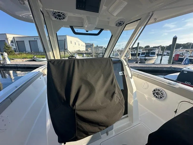 Slide: The Image of 2022 Pursuit S 328 Sport boat interior at marina, featuring covered helm and docked boats. - 2