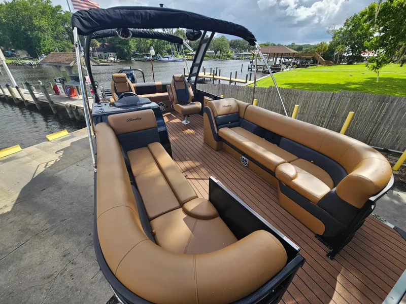 Slide: The Image of 2026 Bentley Pontoons Elite 253 Swingback with luxurious seating and scenic waterfront view. - 10