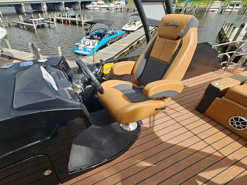 Slide: The Image of 2026 Bentley Pontoons Elite 253 Swingback helm with luxurious captain's chair and sleek dashboard. - 22