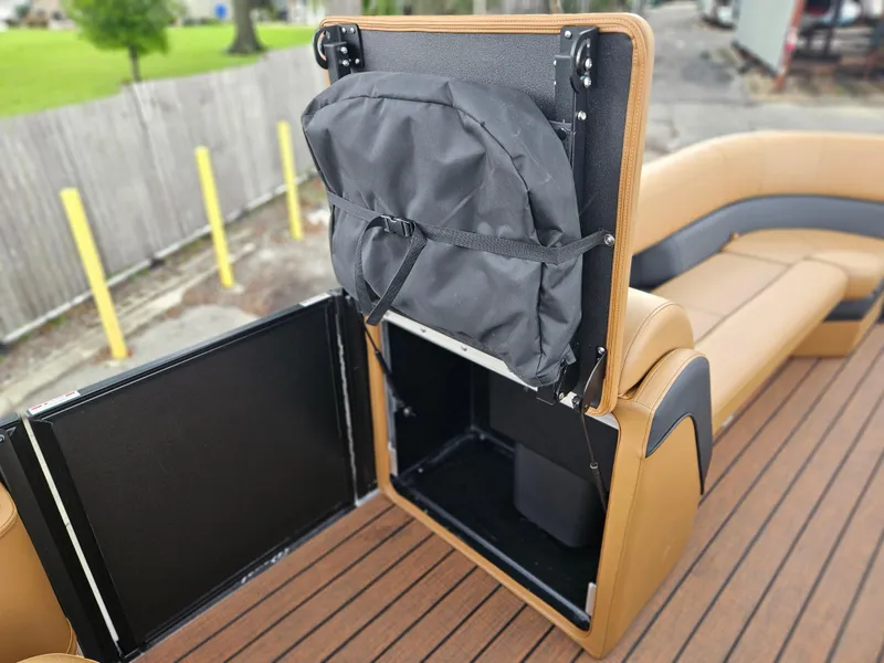 Slide: The Image of 2026 Bentley Pontoons Elite 253 Swingback storage compartment with tan seating and wooden deck. - 30