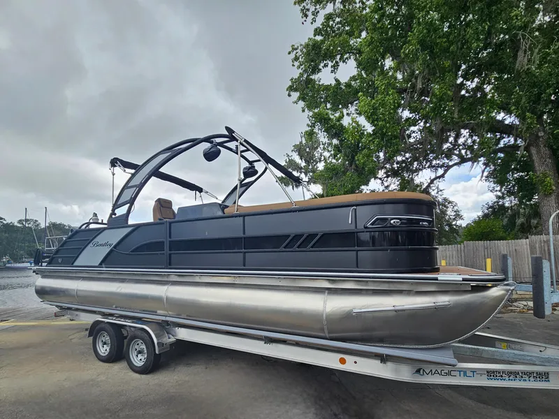 Slide: The Image of 2026 Bentley Pontoons Elite 253 Swingback on trailer, sleek design, parked near water. - 33