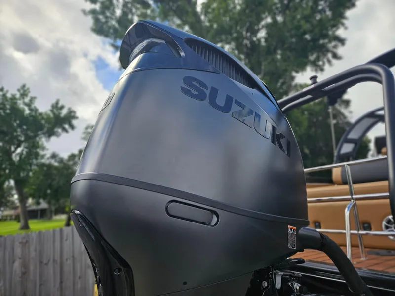 Slide: The Image of Suzuki outboard motor on 2026 Bentley Pontoons Elite 253 Swingback, with trees in the background. - 8