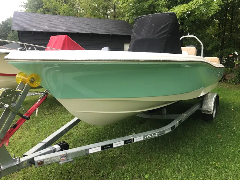 Slide: The Image of 2026 Pioneer 180 Islander boat on trailer, green hull, parked on grass. - 5