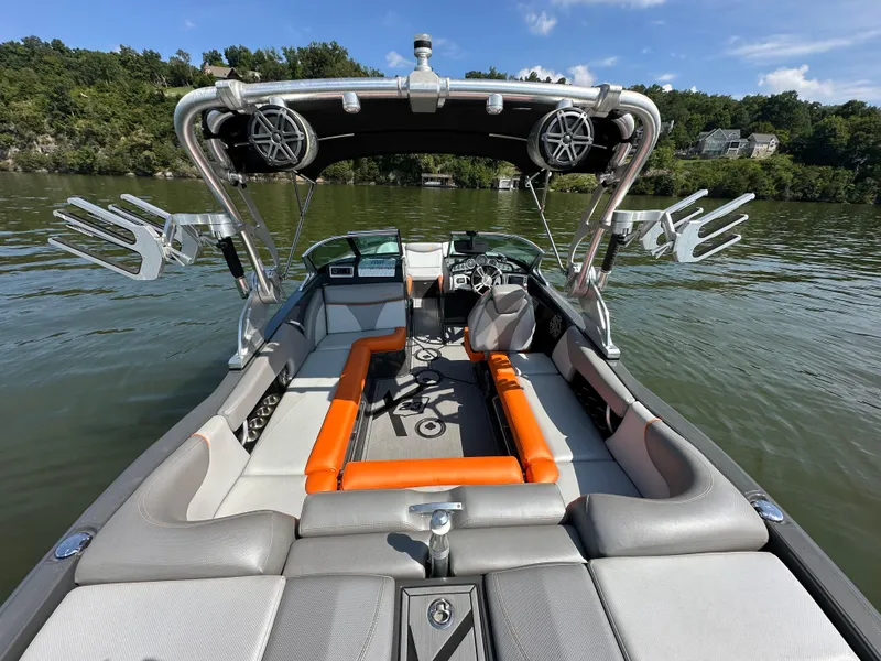Slide: The Image of 2016 MasterCraft X23 boat interior with seating, speakers, and wakeboard racks on a lake. - 11