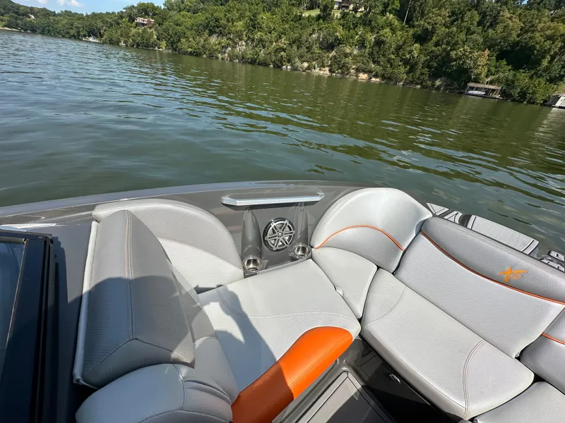 Slide: The Image of 2016 MasterCraft X23 boat interior with gray and orange seating on a lake. - 17