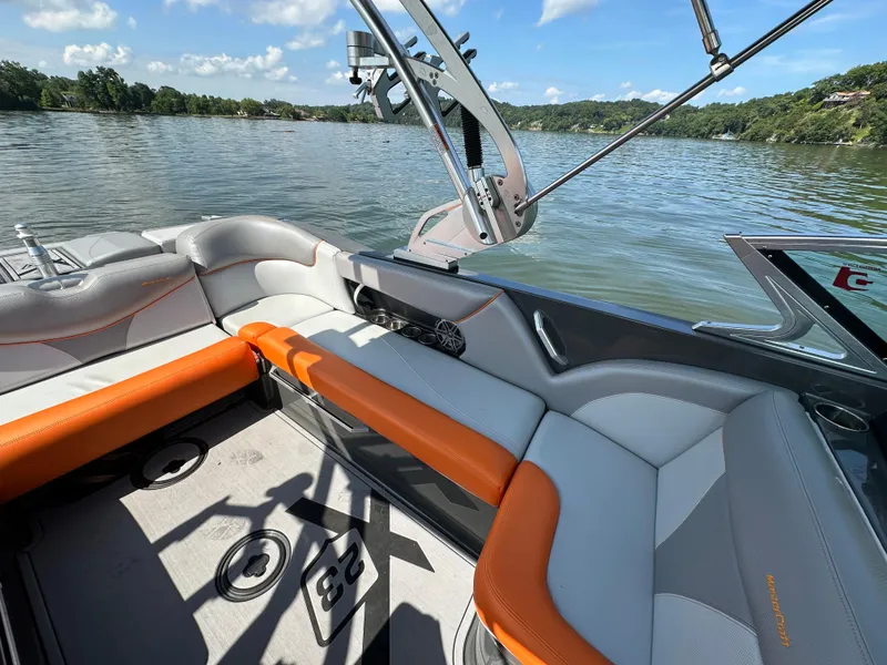Slide: The Image of 2016 MasterCraft X23 boat interior with orange and gray seating on a lake. - 19