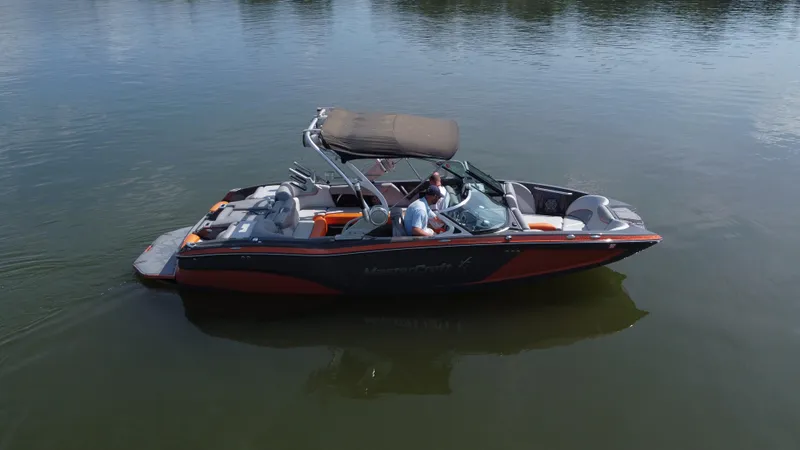 Slide: The Image of 2016 MasterCraft X23 boat on calm water, featuring sleek design and canopy. - 2