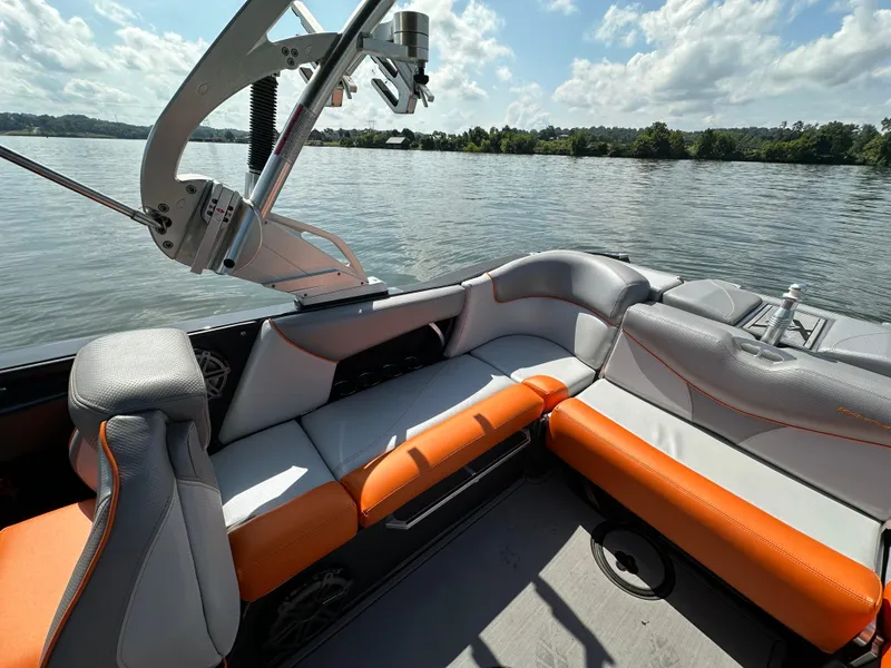 Slide: The Image of 2016 MasterCraft X23 boat interior with orange and gray seating on a sunny lake. - 20