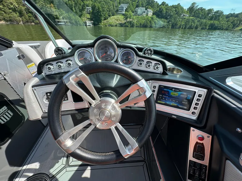 Slide: The Image of 2016 MasterCraft X23 boat dashboard with steering wheel and digital display on a lake. - 21