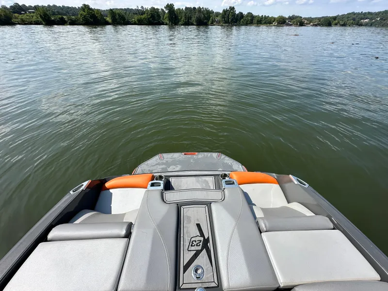 Slide: The Image of 2016 MasterCraft X23 boat on calm lake with scenic shoreline. - 24