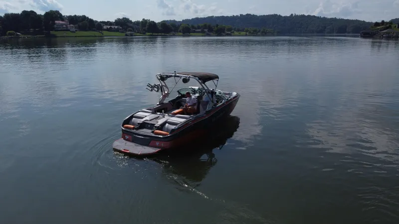 Slide: The Image of 2016 MasterCraft X23 boat cruising on a calm lake with scenic background. - 3