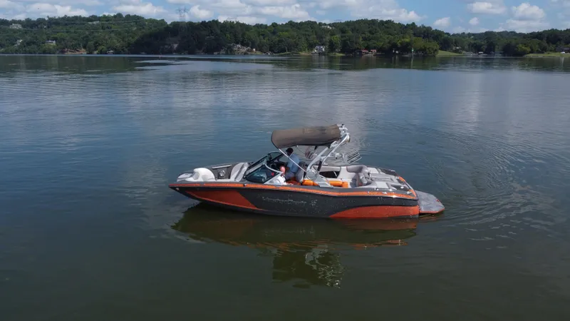 Slide: The Image of 2016 MasterCraft X23 boat on a calm lake with scenic forested background. - 4