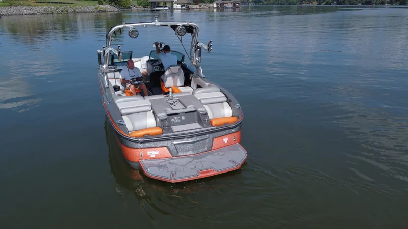 Slide: The Image of 2016 MasterCraft X23 boat on calm lake with passengers, featuring sleek design and modern amenities. - 5