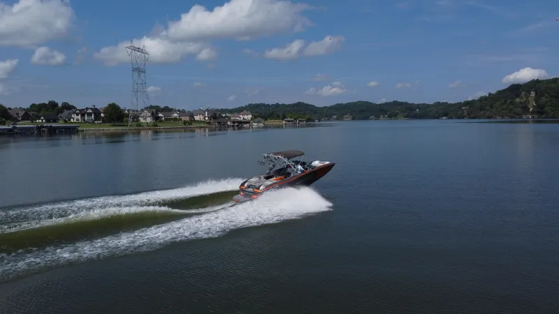 Slide: The Image of 2016 MasterCraft X23 speedboat cruising on a scenic lake under a clear blue sky. - 7