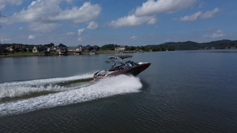 Slide: The Image of 2016 MasterCraft X23 boat cruising on a lake with houses in the background. - 8