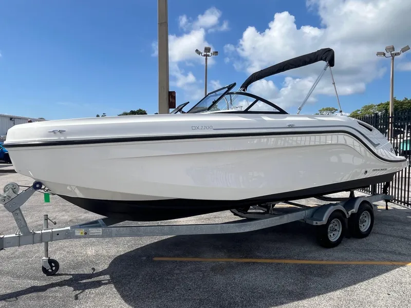 The Image of 2022 Bayliner DX 2200 boat on trailer under clear blue sky. - 0
