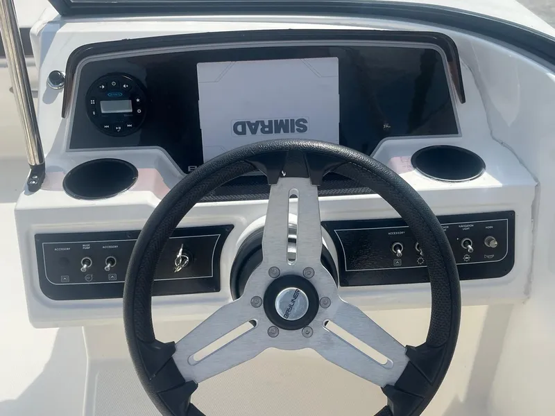 Slide: The Image of Steering wheel and dashboard of 2022 Bayliner DX 2200 boat, featuring controls and cup holders. - 5