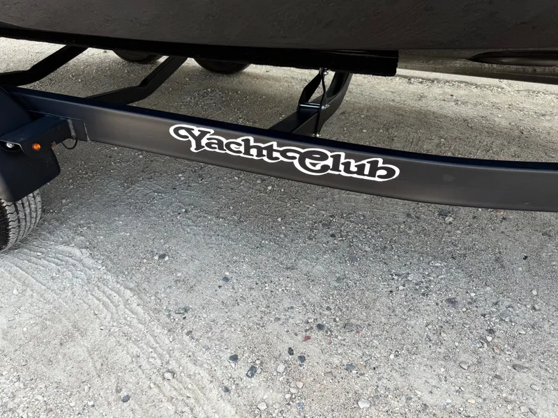 Slide: The Image of Trailer with "Yacht Club" logo for 2019 Cobalt CS23 boat on gravel surface. - 42