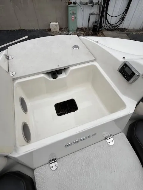 Slide: The Image of 2018 Stingray 235 LR boat storage compartment with cup holders and control panel. - 17