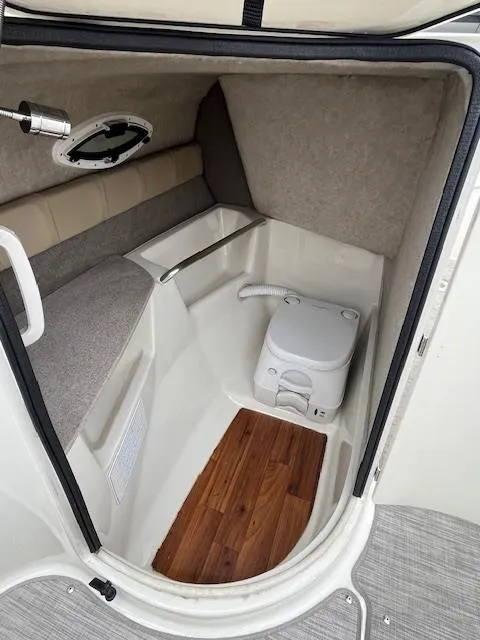 Slide: The Image of 2018 Stingray 235 LR boat interior with compact toilet and wooden flooring. - 20