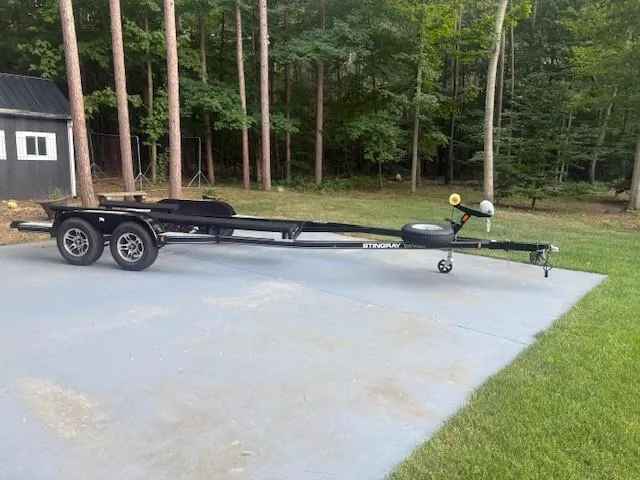 Slide: The Image of 2018 Stingray 235 LR boat trailer parked on concrete near a wooded area. - 26