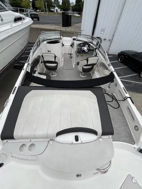 Slide: The Image of 2018 Stingray 235 LR boat with spacious seating and sleek design in a marina setting. - 5