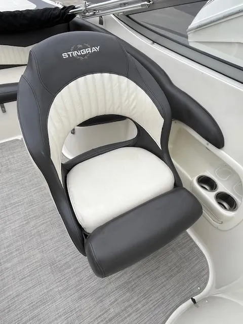 Slide: The Image of 2018 Stingray 235 LR boat seat with black and white upholstery, featuring cup holders. - 8