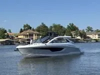 The Image of 2022 Cruisers 42 GLS yacht on a serene lake with houses in the background. - 1