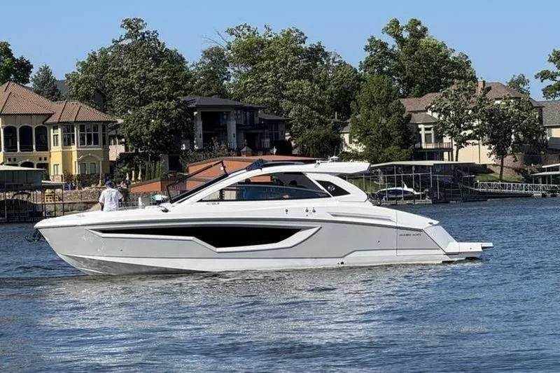 The Image of 2022 Cruisers 42 GLS yacht on a serene lake with waterfront homes. - 0