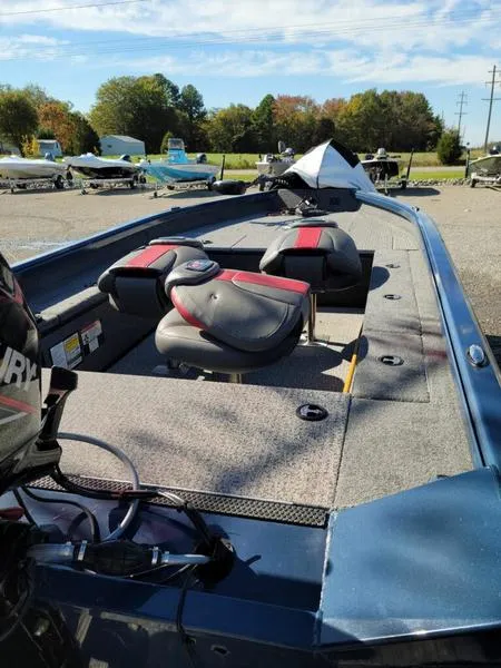 Slide: The Image of 2021 Ranger VS1660T boat with red and black seats, parked outdoors on a sunny day. - 2