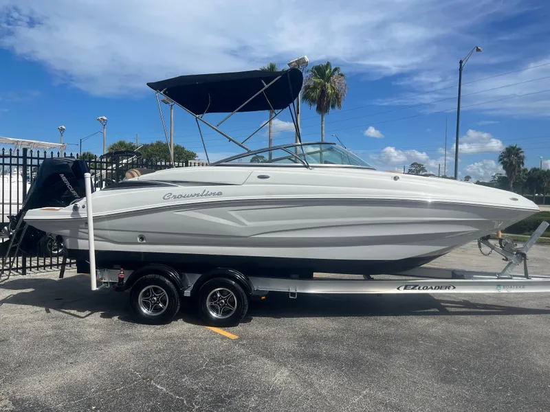 Slide: The Image of 2022 Crownline Eclipse E235 XS boat on trailer, parked outdoors under blue sky. - 4