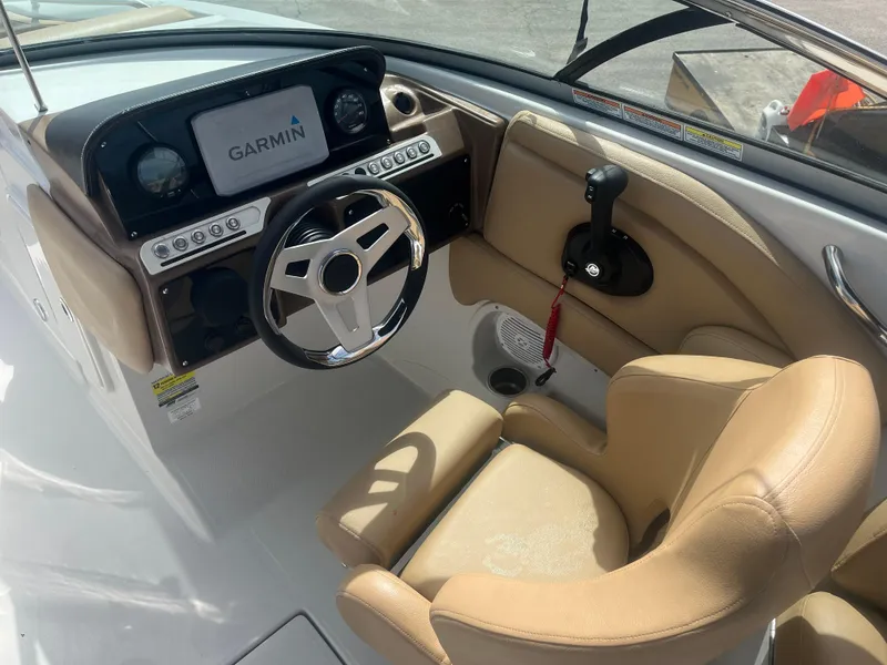 Slide: The Image of 2022 Crownline Eclipse E235 XS boat cockpit with Garmin display and beige seating. - 5