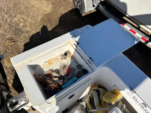 Slide: The Image of Open storage compartment on a 1997 Wellcraft 210 Coastal boat, containing various fishing gear. - 12