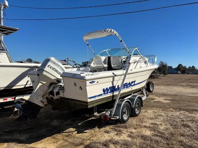 Slide: The Image of 1997 Wellcraft 210 Coastal boat on trailer with Evinrude outboard motor, parked outdoors. - 3